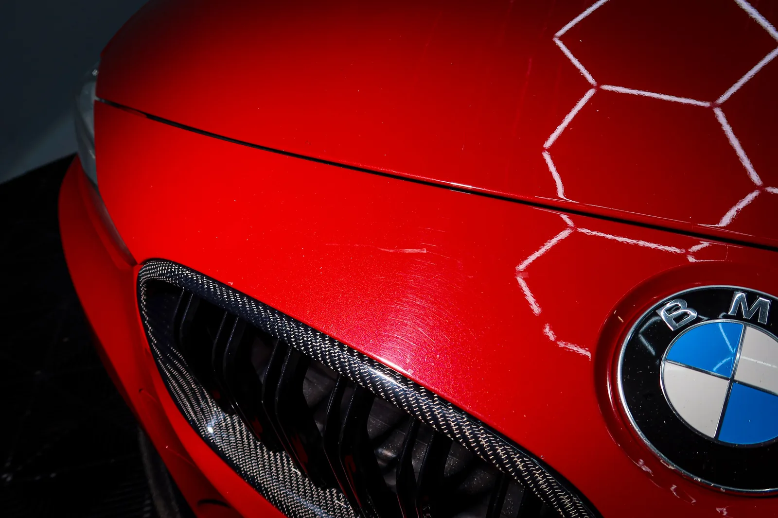 Tourbillons et égratignures fines à l'avant d'une auto rouge, repérés sous l'éclairage du studio à l'inspection